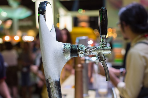 Barman or bartender pouring a draught lager beer from beer tap on counter