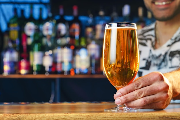 Barman serves glass of cold beer at bar counter in pub