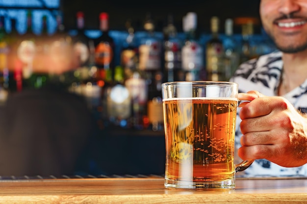 Barman serves glass of cold beer at bar counter in pub