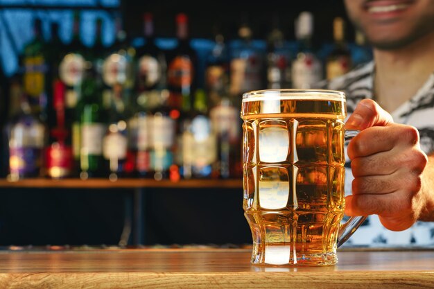 Barman serves glass of cold beer at bar counter in pub