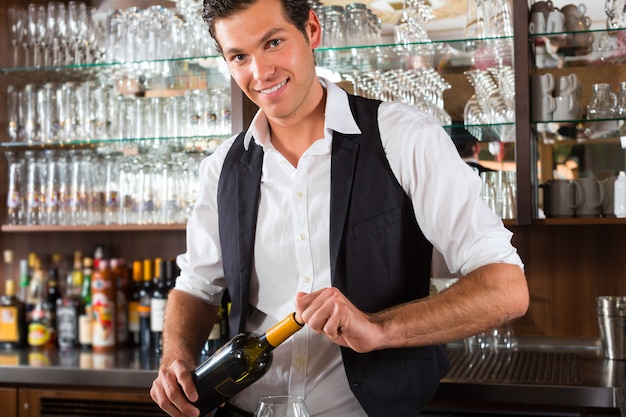 Barman standing behind bar with wine