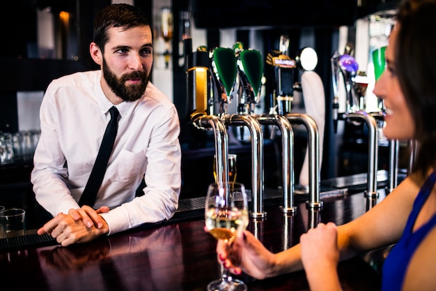 Barman talking with pretty customer in a bar