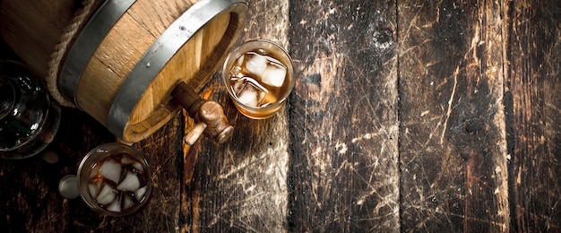 barrel of Scotch whiskey with a glass. On a wooden background.