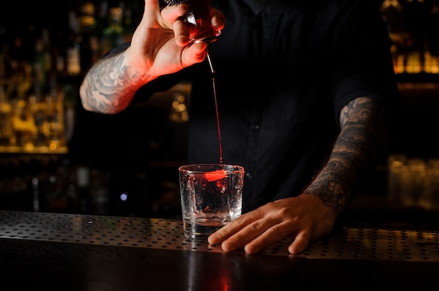 Bartender adding a bitter to the delicious cocktail from the special dasher bottle on the bar counter