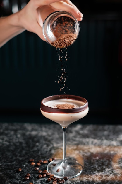 The bartender adds grated chocolate to a cocktail preparing drinks in a bar