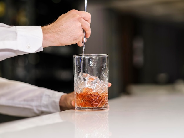 A bartender in the bar is preparing a cocktail