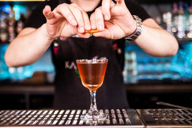 Bartender decorates cocktail with lemon or orange peel Horizontal photo