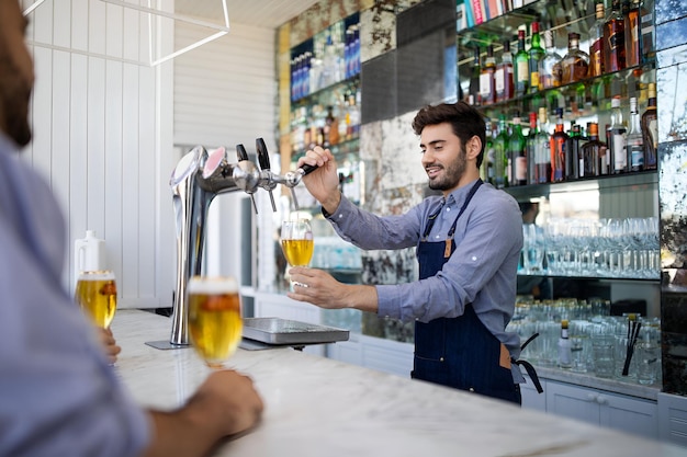 Photo bartender filing beer in a glass from tap