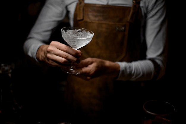 Bartender holds glass with a melted ice