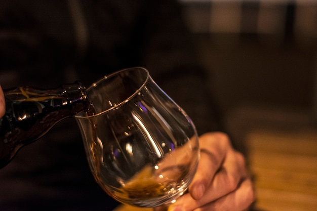 Bartender is pouring black beer in empty glass