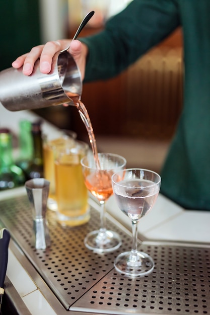 Bartender making a cocktail at the bar: pouring a drink from a shaker into a glass