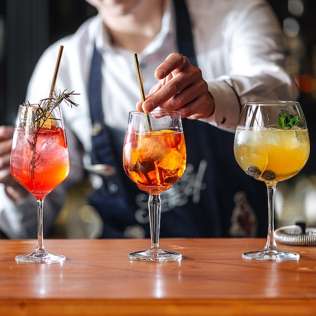 Bartender making fruit alcoholic cocktailes on the wooden desk