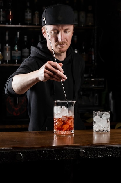 Bartender mixes gin campari and sweet vermouth to prepare the Negroni alcoholic cocktail Bartender prepares traditional Negroni cocktail at the bar