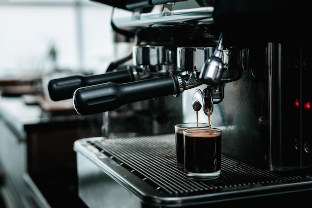 bartender mixing and pouring coffee into cup from coffee machine at counter in small coffee shop