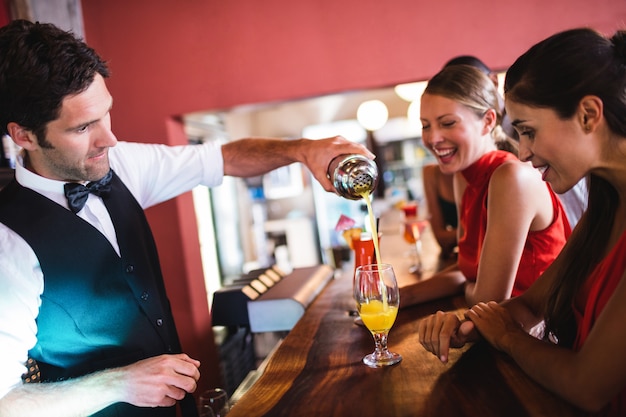 Bartender pouring cocktail in glass at bar counter