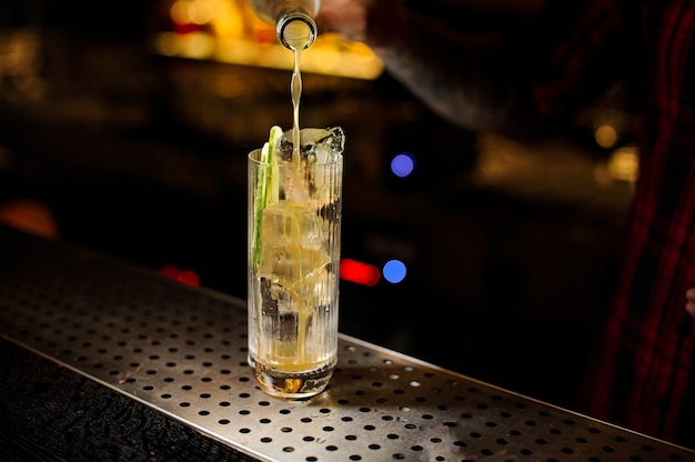 Bartender pouring a delicious Lynchburg lemonade cocktail from the bottle to a glass on the bar counter