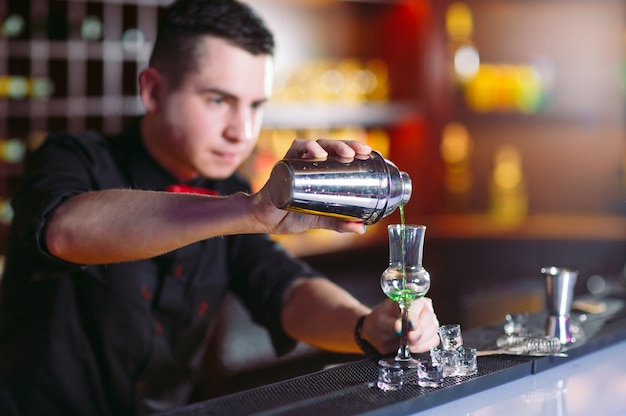 Bartender pouring fresh cocktail in fancy glass