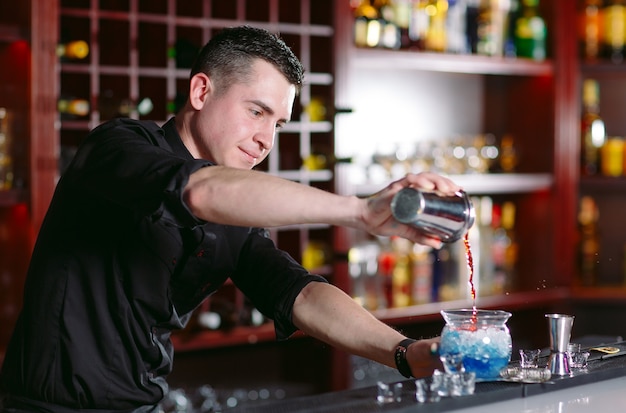 Bartender pouring fresh cocktail in fancy glass