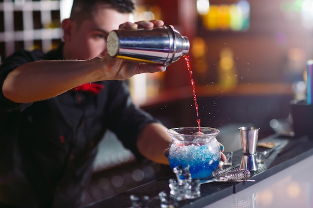 Bartender pouring fresh cocktail in fancy glass