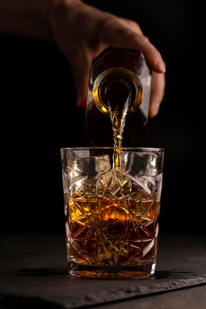 Bartender pours whiskey or rum into a glass