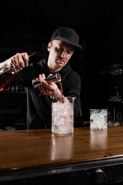 Bartender prepares traditional Negroni cocktail at the bar Bartender mixes gin campari and sweet vermouth to prepare the Negroni alcoholic cocktail