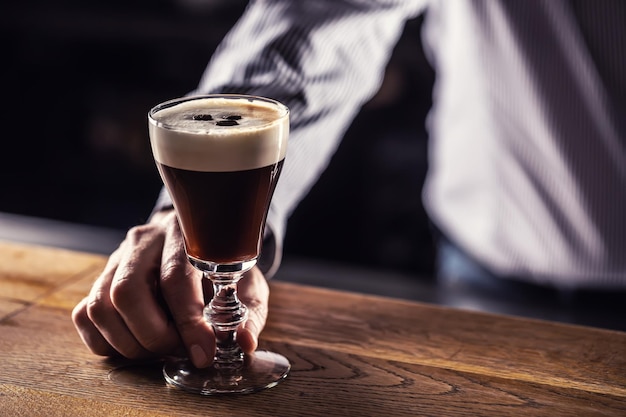 The bartender serves prepared Irish coffee to guests in the cafe