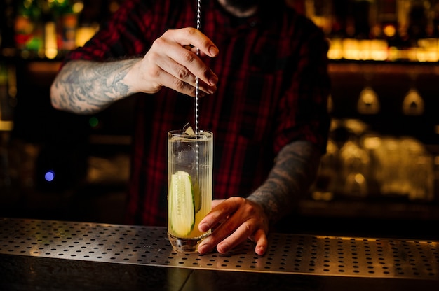 Bartender stirring a Lynchburg lemonade cocktail with the spoon in the glass on the bar counter