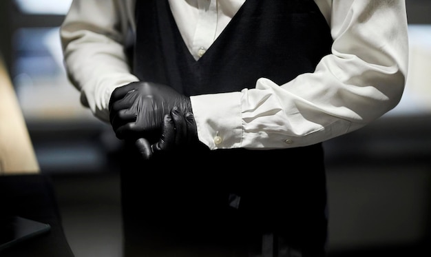 bartender in white shirt, black apron, black gloves. close-up of the waiter's hands in gloves