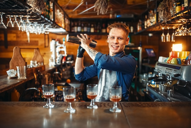 Bartender works with shaker at the bar counter