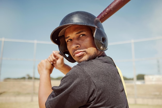 Baseball player man and fitness athlete train for baseball competition on pitch field outdoors Sports wellness workout healthy lifestyle and man in sport safety helmet with bat at stadium outside