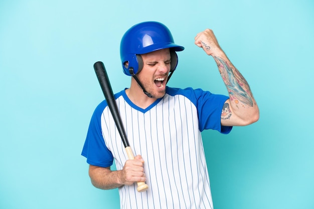 Baseball player with helmet and bat isolated on blue background celebrating a victory