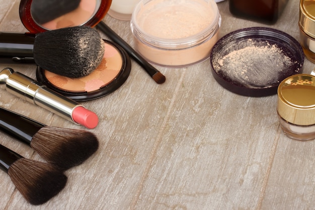 Basic make-up products - foundation, powder and lipstick on gray table with copy space