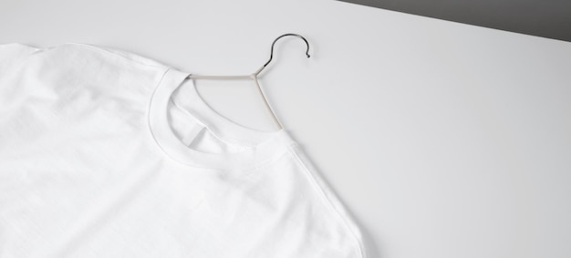 Basic white tshirt and hanger on table Mock up for branding tshirt Copy space