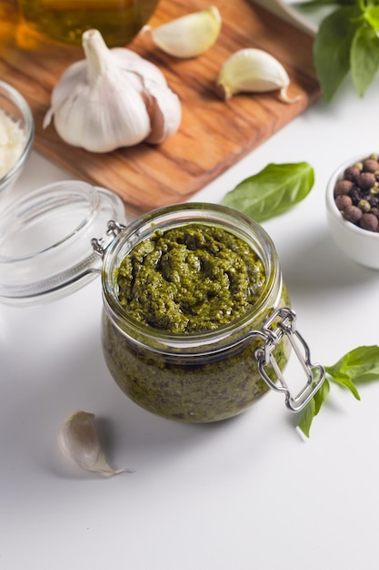 Basil pesto sauce in a jar. Ingredients for cooking, cheese, parmesan, garlic, olive oil.