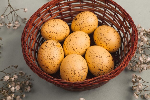 A basket of eggs with a bunch of flowers on the side