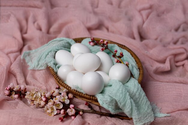 A basket of eggs with flowers on a pink blanket