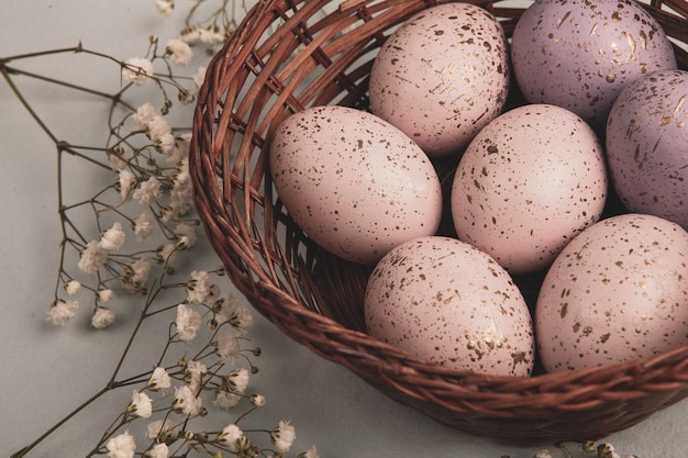 A basket of eggs with purple and pink speckled eggs on a table.