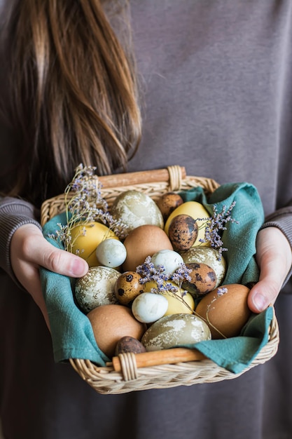 Basket in female hands with eggs dyed with natural ecofriendly dyes for easter vertical view