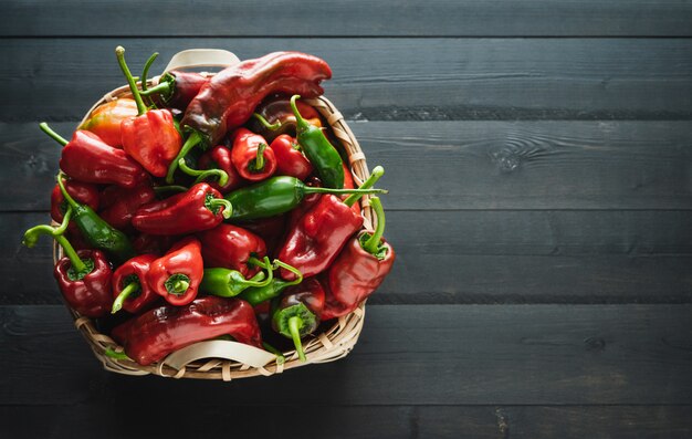 Basket of red and green peppers on a black wooden