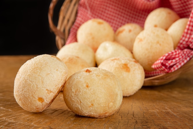 Basket with checkered cloth with cheese breads on rustic wood surface