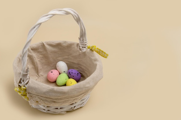 Basket with colorful Easter eggs on a beige background with copy space