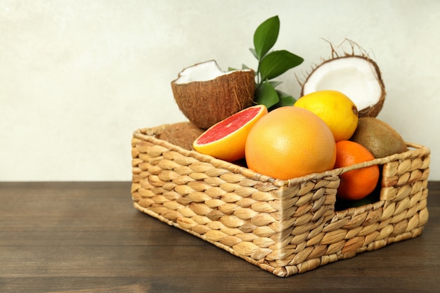 Basket with exotic fruits on wooden table.