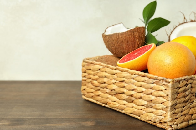 Basket with exotic fruits on wooden table.