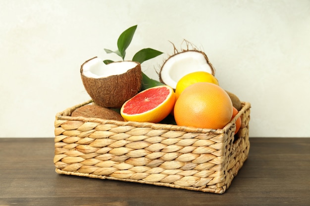 Basket with exotic fruits on wooden table.