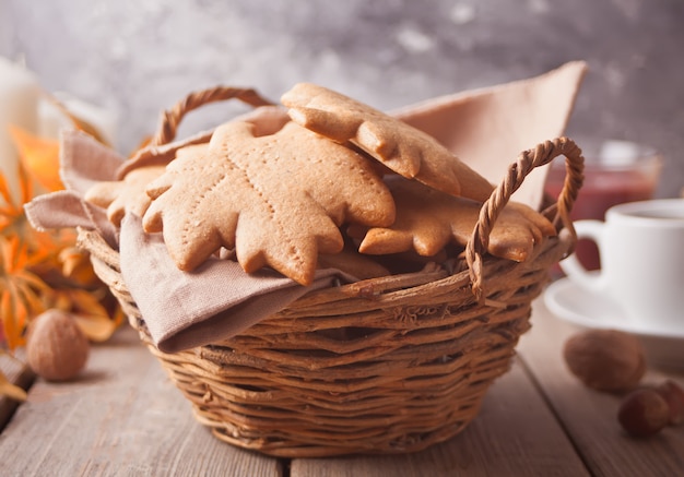 Basket with homemade cookies, cuop of coffee, leaves on the wooden table. Autumn harvest. Autumn concept. Top view.