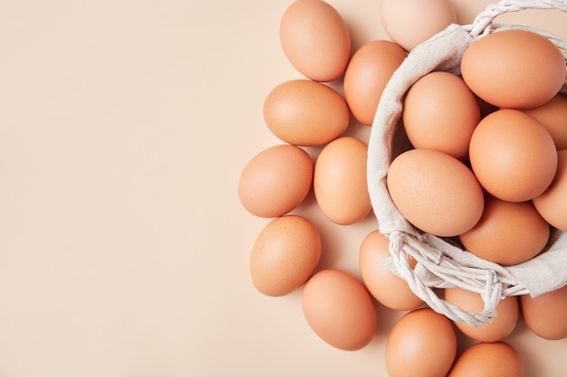 Basket with homemade eggs centered in the middle of the picture on beige background