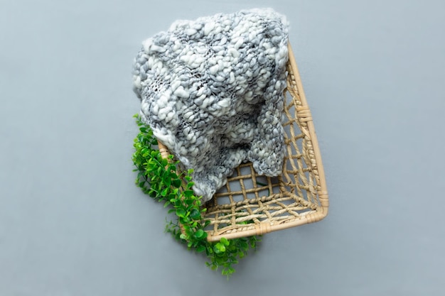 A basket with a piece of wool on it and a green plant on the top.