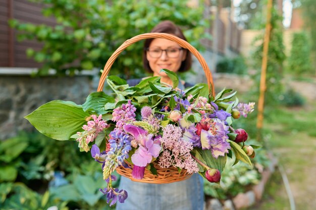 Basket with spring garden flowers in the hands of woman