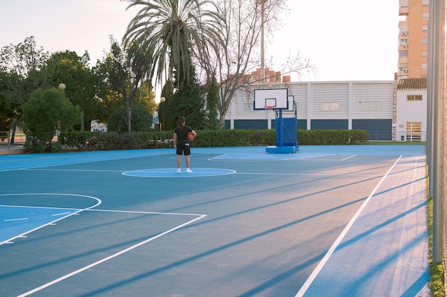 Basketball court with one person in the middle looking to the basket