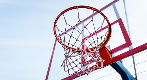 Basketball hoop close-up in the sports hall, bottom view. Against the backdrop of a sunny blue sky.